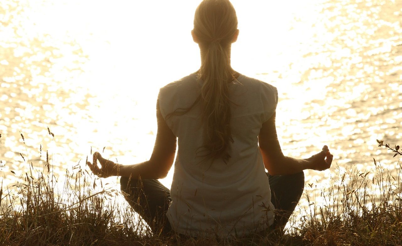 A woman meditating by the river side